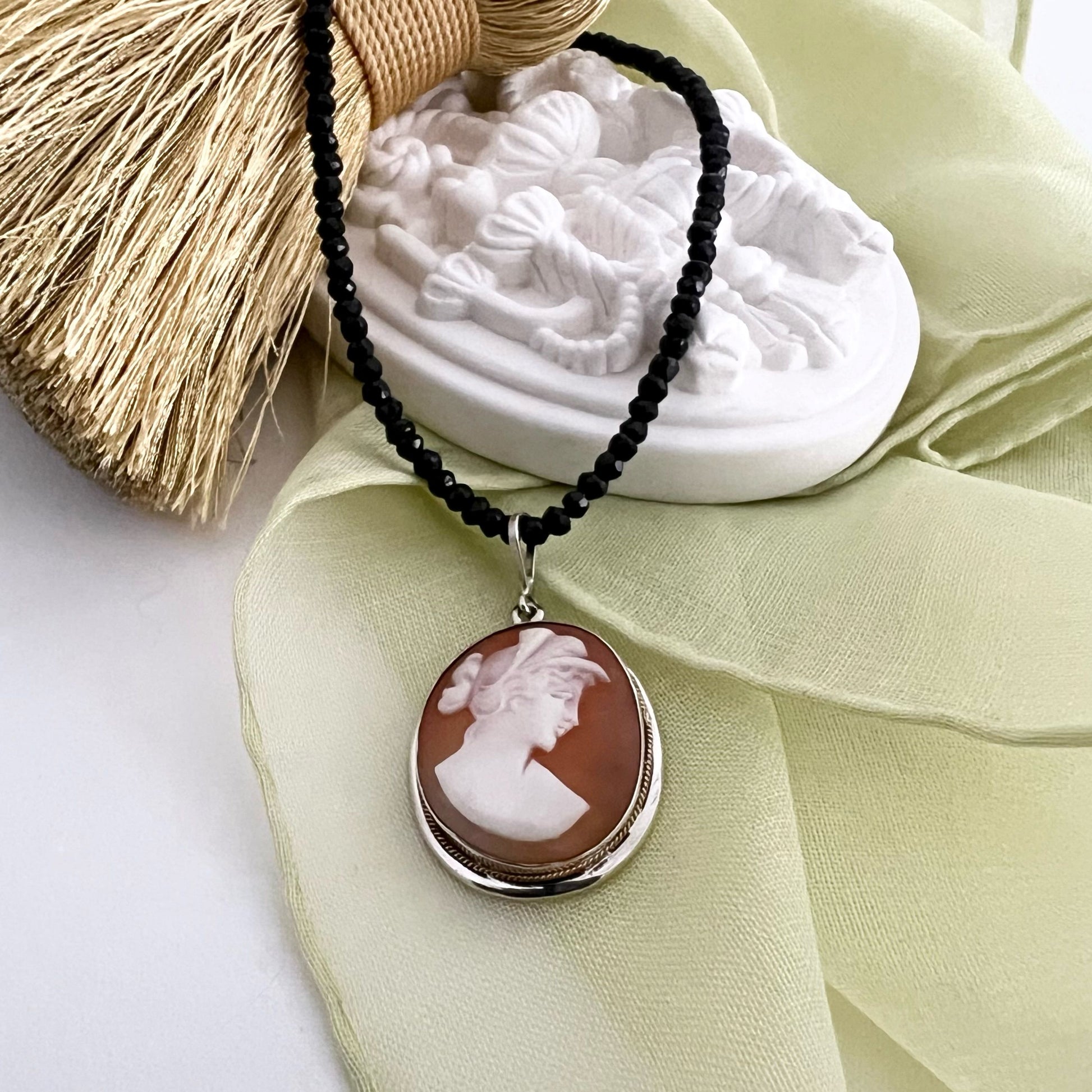 Antique sterling silver cameo necklace adorned with elegant black tourmaline pearls. The cameo depicts a profile of a woman in the roman style.
